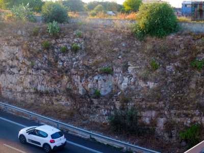 Le pareti rocciose tra le quali scorre la superstrada mostrano in modo evidente i bianchi livelli calcarei accanto ad ammassi irregolari di calcare rossiccio
